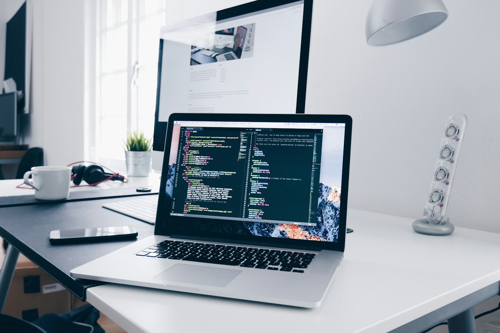 コードを表示したノートパソコンと開発用のデスク